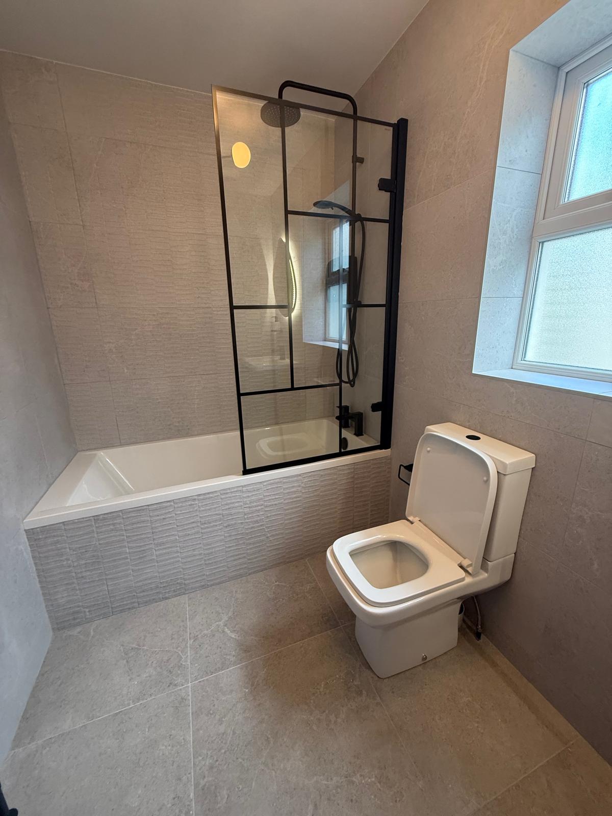 Finished bathroom with stone-look tiling and dark fittings